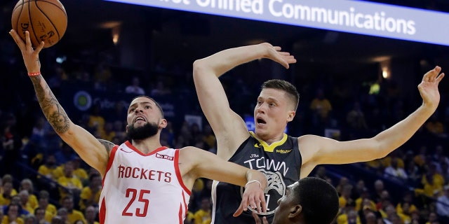 Houston Rockets' Austin Rivers (25) drives to the basket as Golden State Warriors' Jonas Jerebko, right rear, defends during the first half of Game 2 of a second-round NBA basketball playoff series in Oakland, Calif., Tuesday, April 30, 2019. (Associated Press)