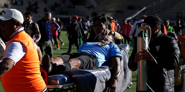 Referee Victor Hugo Hurtado is transported off the field to the hospital after fainting during a soccer game between the Always Ready team and Oriente Petrolero team, part of the "Apertura" local soccer tournament in El Alto, Bolivia, Sunday, May 19, 2019. (AP Photo/Juan Carlos Usnayo)