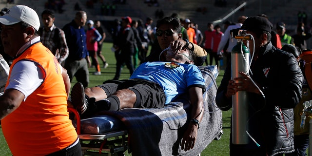 Referee Victor Hugo Hurtado is transported off the field to the hospital after fainting during a soccer game between the Always Ready team and Oriente Petrolero team, part of the "Apertura" local soccer tournament in El Alto, Bolivia, Sunday, May 19, 2019. (AP Photo/Juan Carlos Usnayo)