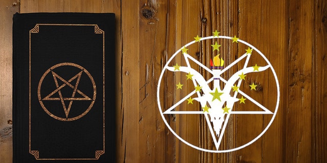 Close-up on a black book with a gilded Reverse Pentagram on a brown wood board.