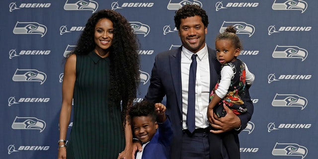 O quarterback do Seattle Seahawks NFL Russell Wilson posa para fotos com sua esposa Ciara, sua filha Sienna e o filho de Ciara, Future, quarta-feira, 17 de abril de 2019, em Renton, Washington, após uma coletiva de imprensa. No início da semana, Wilson assinou uma extensão de US $ 140 milhões e quatro anos com a equipe.
