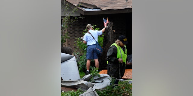 Letter carrier James Hurtado resets a small U.S. flag into a tree stump while delivering the mail Saturday May 18, 2019 on S. 6th St. in Abilene.