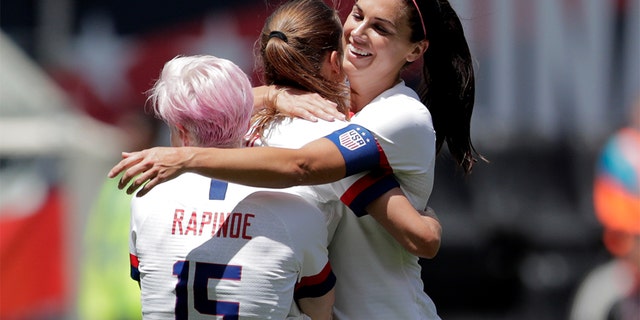 Unites States forward Megan Rapinoe (15) and forward Alex Morgan (13) hugging teammate forward Tobin Heath, center, after she scored a goal against Mexico. (AP Photo/Julio Cortez)