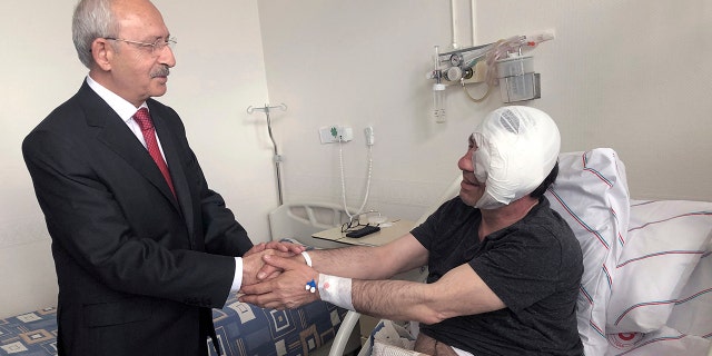 Yavuz Selim Demirag, a Turkish journalist critical of President Recep Tayyip Erdogan's government and its nationalist allies, shakes hands with visiting Kemal Kilicdaroglu, the leader of Turkey's main opposition Republican People's Party, second left, as he rests in a hospital bed in Ankara, Turkey, Saturday, May 11, 2019. Yenicag newspaper says Saturday columnist Demirag was beaten by a group of about five or six people with baseball bats outside his home after appearing on a TV show late Friday.(AP Photo/Burhan Ozbilici)