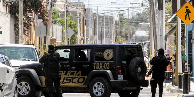 Mexican police members guarding the area where forensic service personnel worked at a clandestine grave inside a farm Saturday in Zapopan, Mexico.