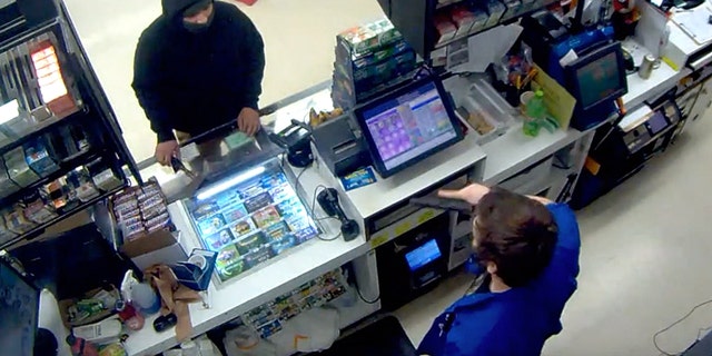 Image of surveillance video showing a convenience store in Oregon taking out a gun from a so-called masked thief who had a hatchet.