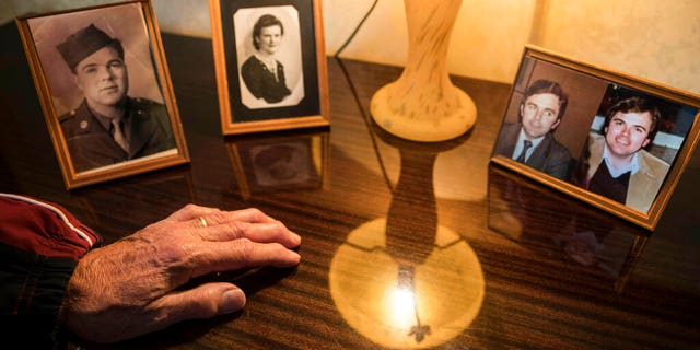Andre Gantois's hand rests by the photos of his parents, Wilburn Henderson, left, and mother, Irene Gantois, and at the right a split portrait showing Andre Gantois, left, and his brother Allen Henderson, as young men.