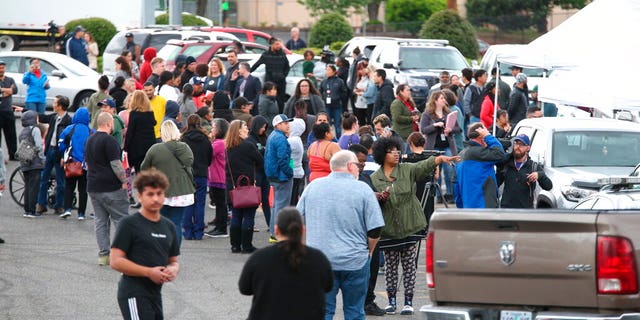 Students gather outside Parkrose High School during a lockdown after a man armed with a gun was wrestled to the ground by a staff member. (Dave Killen/The Oregonian via AP)