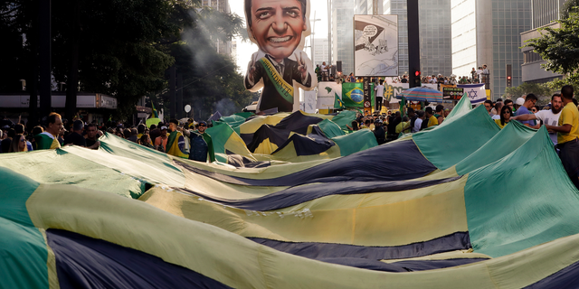 Supporters of Brazil's President Jair Bolsonaro feature a large, inflatable doll in his image as they demonstrate along Paulista Avenue in Sao Paulo, Brazil, Sunday, May 26, 2019. The pro-Bolsonaro rally follows anti-government protests against education budget cuts as the president also battles an uncooperative Congress, a family corruption scandal and falling approval ratings after five months in office. (AP Photo/Andre Penner)