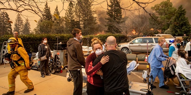 This Nov. 8 photo shows Nurse Cassie Lerossignol hugging a co-worker as the Feather River Hospital burns, victim of the Camp Fire raging in Paradise, Calif. (AP Photo/Noah Berger, File)