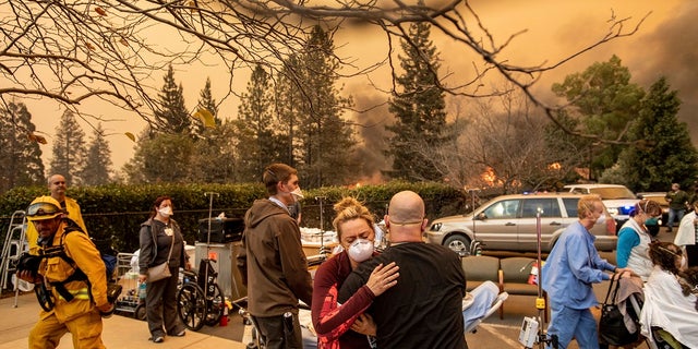 This Nov. 8 photo shows Nurse Cassie Lerossignol hugging a co-worker as the Feather River Hospital burns, victim of the Camp Fire raging in Paradise, Calif. (AP Photo/Noah Berger, File)