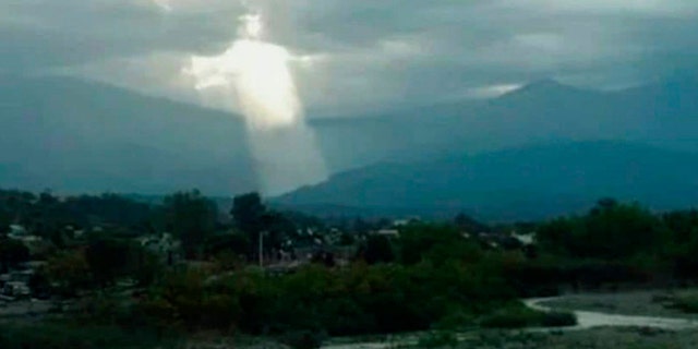 Pic shows: The picture of the Jesus Christ figure in the sky. ARGENTINA: A photo of a Jesus Christ-like figure with his hands outstretched beaming down through the cloudy sky has caused a furor in Argentina, where it was taken.
