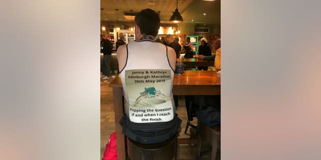 Jonny, a software engineer, kept the proposal quiet by secretly having a top made with the words "Kathryn, will you marry me?" on the front and "Popping the question if and when I reach the finish" on the back.