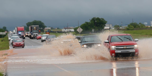 Vehicles drive through floodwater on US Highway 66 following heavy rains Tuesday, May 21, 2019, in El Reno, Okla.