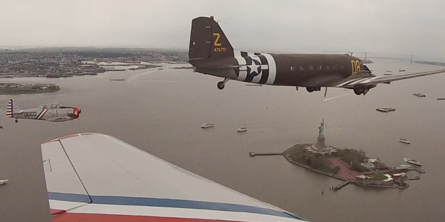 The Geico Skytypers and a Douglas C-47 military transport plane fly by the Statue of Liberty Thursday.