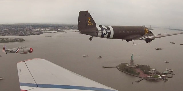 The Geico Skytypers and a Douglas C-47 military transport plane fly by the Statue of Liberty Thursday.