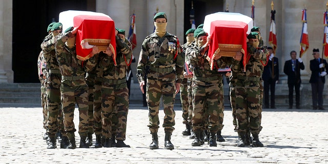 Special forces soldiers carry the flag-drapped coffins of late special forces soldiers Cedric de Pierrepont and Alain Bertoncello, who were killed in a night-time rescue of four foreign hostages including two French citizens in Burkina Faso last week, during a national tribute at the Invalides, in Paris, Tuesday, May 14, 2019. France is honoring two special forces officers killed in an operation that freed four hostages held in Burkina Faso.
