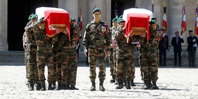 Special forces soldiers carry the flag-drapped coffins of late special forces soldiers Cedric de Pierrepont and Alain Bertoncello, who were killed in a night-time rescue of four foreign hostages including two French citizens in Burkina Faso last week, during a national tribute at the Invalides, in Paris, Tuesday, May 14, 2019. France is honoring two special forces officers killed in an operation that freed four hostages held in Burkina Faso.