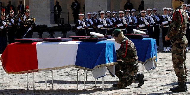 A special forces soldier places a rope between the flag-drapped coffins of late special forces soldiers Cedric de Pierrepont and Alain Bertoncello, who were killed in a night-time rescue of four foreign hostages including two French citizens in Burkina Faso last week, during a national tribute at the Invalides, in Paris, Tuesday, May 14, 2019. France is honoring two special forces officers killed in an operation that freed four hostages held in Burkina Faso.