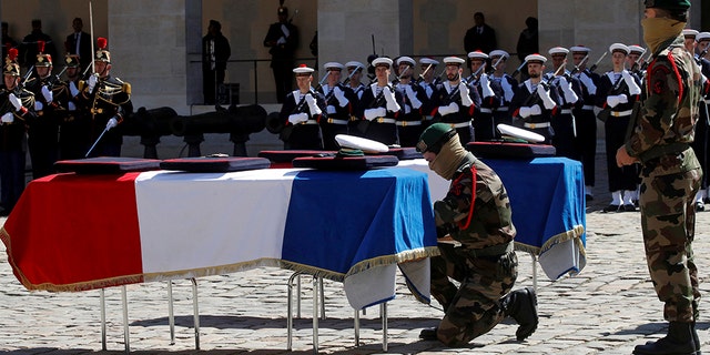 A special forces soldier places a rope between the flag-drapped coffins of late special forces soldiers Cedric de Pierrepont and Alain Bertoncello, who were killed in a night-time rescue of four foreign hostages including two French citizens in Burkina Faso last week, during a national tribute at the Invalides, in Paris, Tuesday, May 14, 2019. France is honoring two special forces officers killed in an operation that freed four hostages held in Burkina Faso.