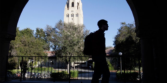 A Stanford University student walks in front of Hoover Tower on the Stanford University campus in Palo Alto, Calif.