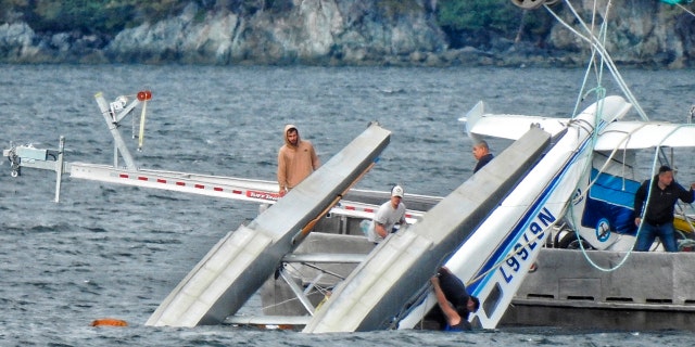 This Monday, May 20, 2019 photo provided by Aerial Leask shows good Samaritans off of fishing vessels attempting to bring in a floatplane that crashed in the harbor of Metlakatla, Alaska. Officials said the pilot and passenger aboard the plane died, and the National Transportation Safety Board is investigating the crash. (Aerial Leask via AP)