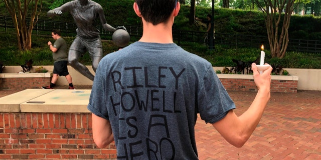 David Belnap, a sophomore at the University of North Carolina at Charlotte, displays a t-shirt in Charlotte, N.C., Wednesday, May 1, 2019, in support of Riley Howell, a classmate who was killed while confronting a gunman inside a classroom on Tuesday.