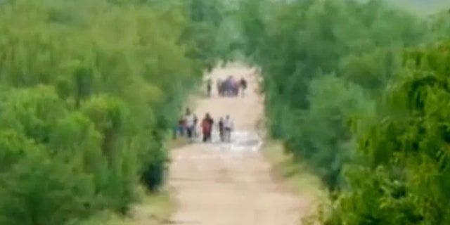 Migrants are seen walking down a road at a portion of the U.S.-Mexico border one top official is calling "ground zero" for illegal crossings.