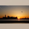 The sun rises behind the skyline of lower Manhattan, One World Trade Center and the Statue of Liberty in New York City, April 29, 2019.
