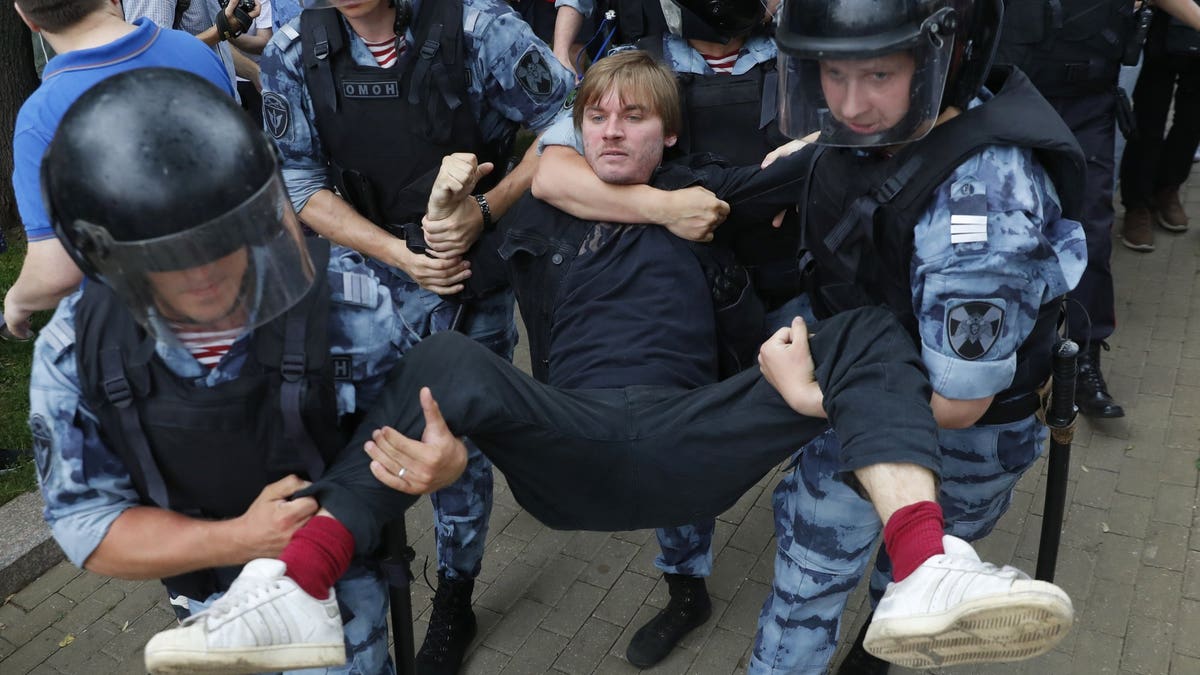 Police officers detain a protester during a march in Moscow, Russia, Wednesday, June 12, 2019. Police and hundreds of demonstrators are facing off in central Moscow at an unauthorized march against police abuse in the wake of the high-profile detention of a Russian journalist. More than 20 demonstrators have been detained, according to monitoring group.