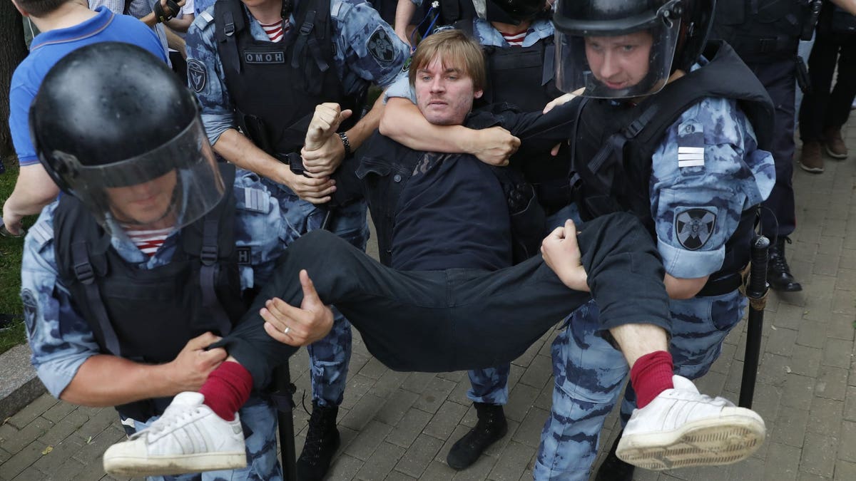 Police officers detain a protester during a march in Moscow, Russia, Wednesday, June 12, 2019. Police and hundreds of demonstrators are facing off in central Moscow at an unauthorized march against police abuse in the wake of the high-profile detention of a Russian journalist. More than 20 demonstrators have been detained, according to monitoring group.