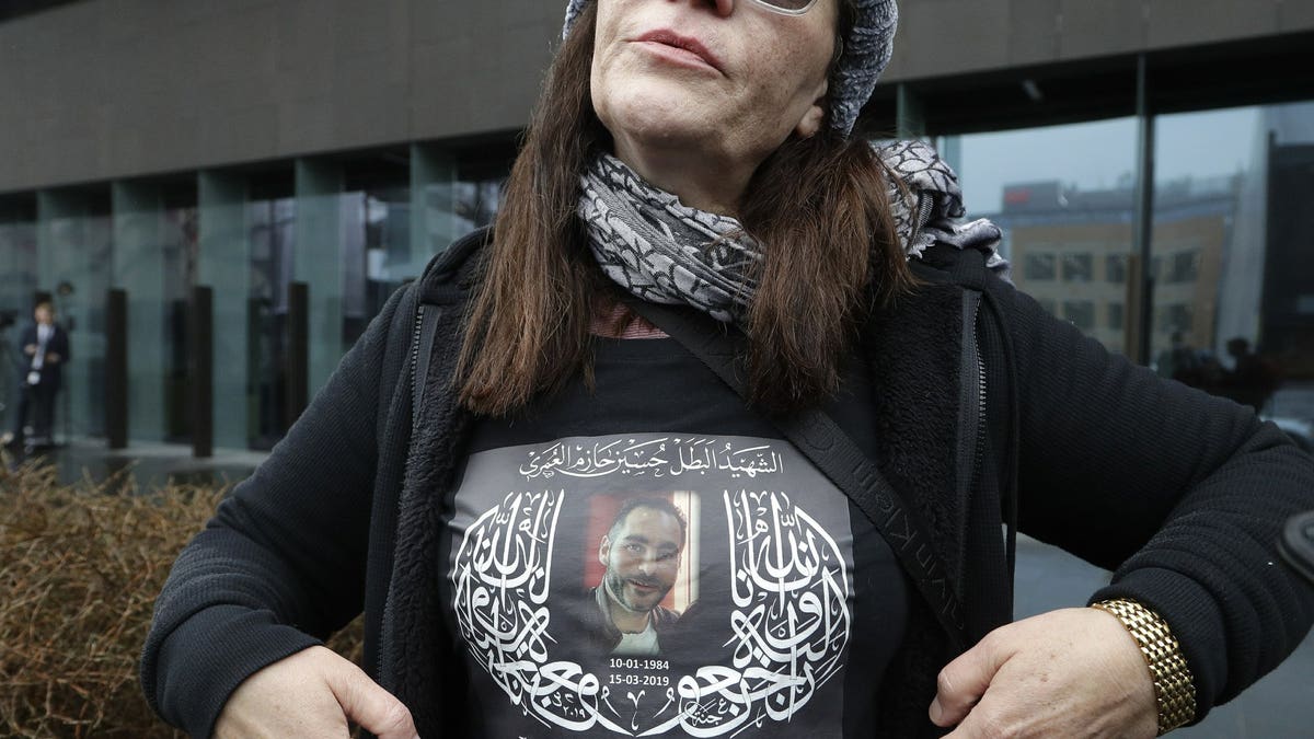 Janna Ezat, mother of Al Noor mosque shooting victim, Hussein Al-Umari shows a shirt bearing his photo outside the Christchurch District Court in Christchurch, New Zealand, Friday, June 14, 2019. Brenton Tarrant, the man accused of killing 51 people at two Christchurch mosques on March 15, 2019, pleaded not guilty to all the charges filed against him Friday June 14.