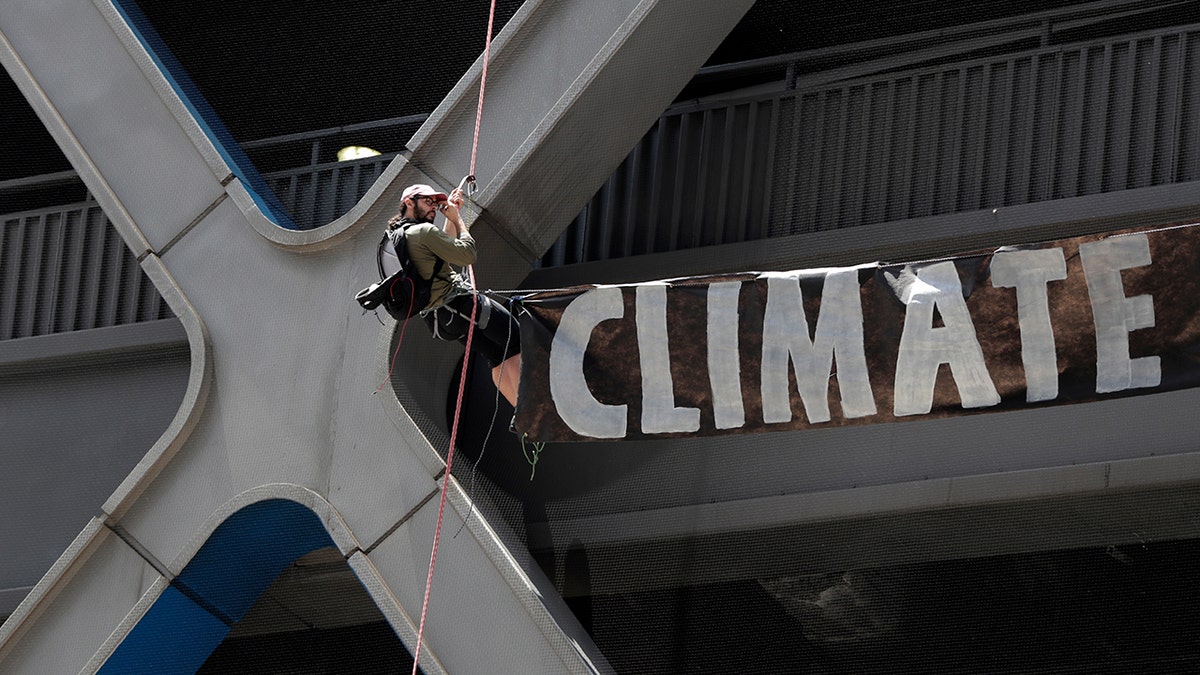 A man rappels down the side of the Port Authority Building with a sign during a climate change rally on Saturday in New York City.