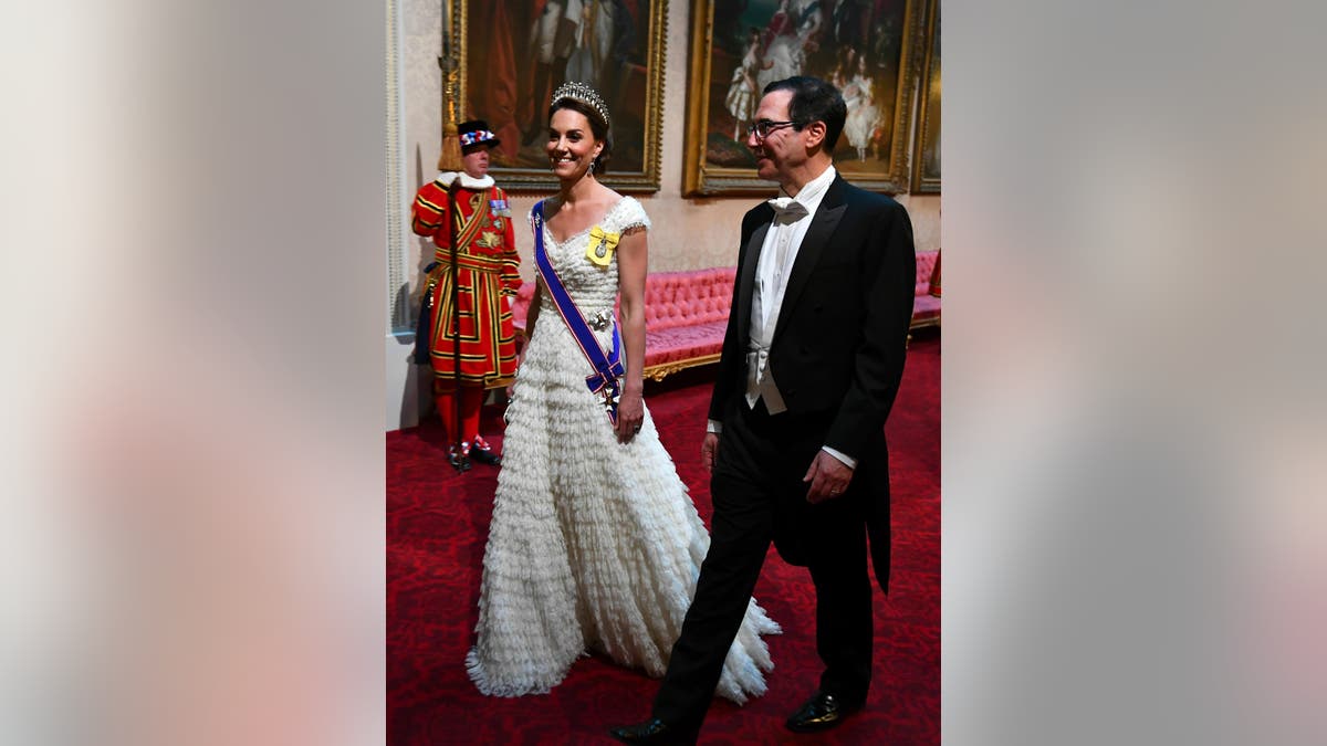Kate, the Duchess of Cambridge and United States Secretary of the Treasury, Steven Mnuchin arrive through the East Gallery ahead of the State Banquet at Buckingham Palace in London, Monday, June 3, 2019. (Victoria Jones/Pool Photo via AP)