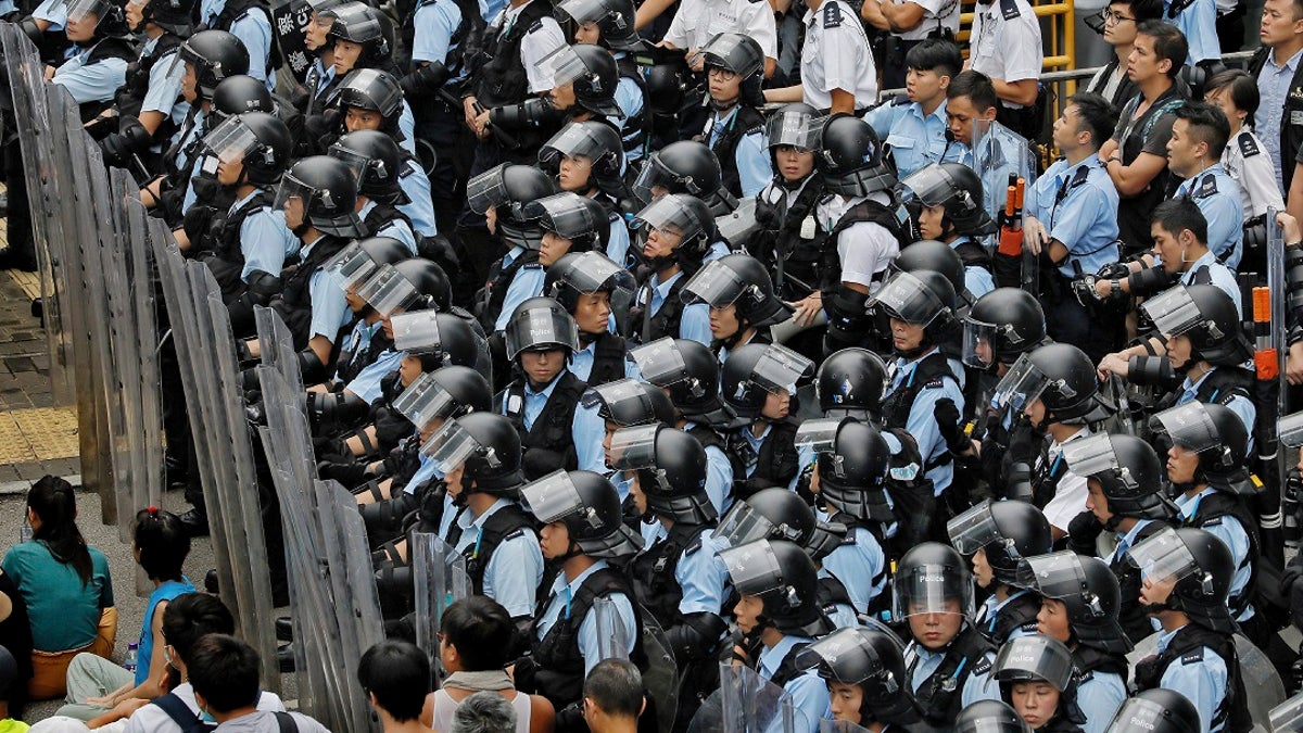 Policemen in anti-riot gear stand watch as the protesters gather outside the Legislative Council in Hong Kong, Wednesday, June 12, 2019. Government officials in Hong Kong are bracing for a showdown as protesters and police continue to face off into the early morning hours outside the semiautonomous Chinese territory's legislature ahead of Wednesday's debate over changes allowing extradition to the Chinese mainland. (AP Photo/Vincent Yu)