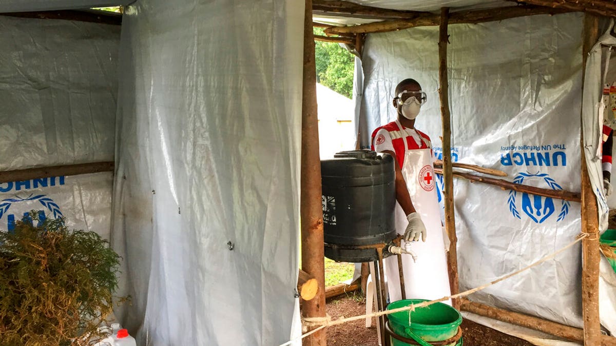 This photo taken Monday, June 10, 2019 and released by the International Rescue Committee (IRC), shows an Ebola screening checkpoint where people crossing from Congo go through foot and hand washing with a chlorine solution and have their temperature taken, at the Bunagana border crossing with Congo, in western Uganda.