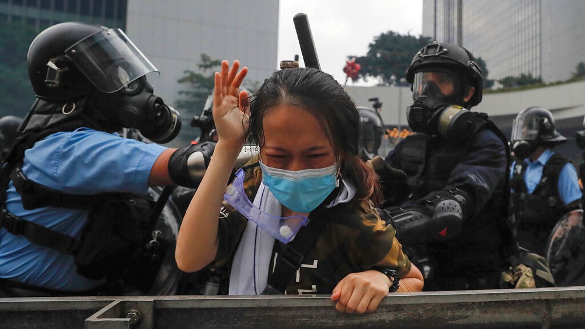 A protester reacts as she tackled by riot police during a massive demonstration outside the Legislative Council in Hong Kong, Wednesday, June 12, 2019. Hong Kong police have used tear gas and high-pressure hoses against thousands of protesters opposing a highly controversial extradition bill outside government headquarters.