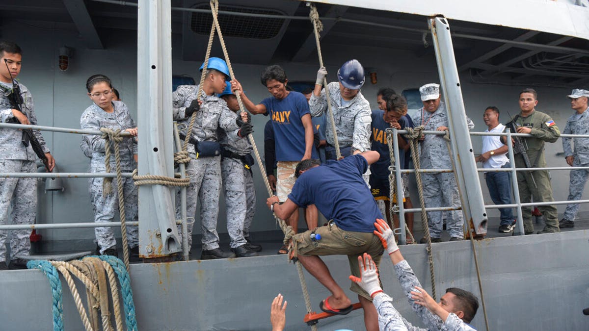 Rescued Filipino fishermen transfer to another ship as they head back to shore in Occidental Mindoro province, Philippines on Friday June 14, 2019. 