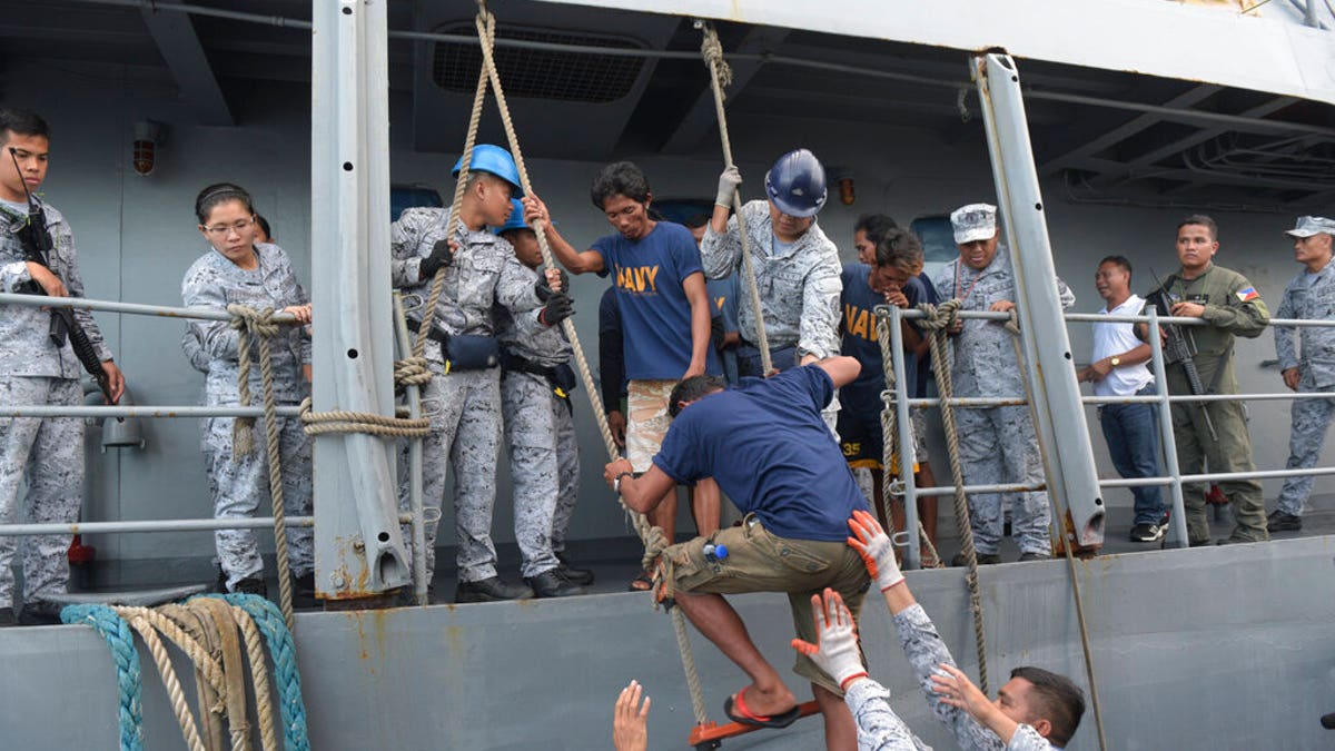 Rescued Filipino fishermen transfer to another ship as they head back to shore in Occidental Mindoro province, Philippines on Friday June 14, 2019.
