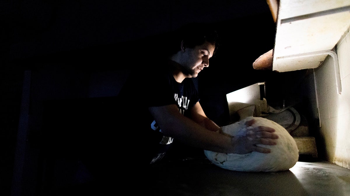 A pizza maker uses battery powered lamps to illuminate his work space during a blackout inside the delivery-only pizza shop in Buenos Aires, Argentina, Sunday, June 16, 2019. A widespread power failure early Sunday morning left a large section of South America, including all of Argentina and Uruguay, without power. AP Photo/Tomas F. Cuesta)