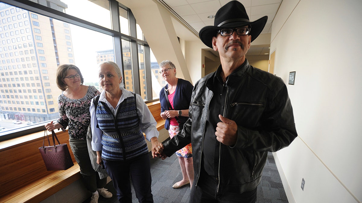 Timothy Hoffman, right, father of slain teenager Cynthia Hoffman receives support from Edie Grunwald, left, who's son David Grunwald was murdered in Nov. 2016, as they entered a Superior courtroom for the arraignment of Cynthia's murder suspects in the Nesbett Courthouse on Tuesday, June 18, 2019 in Anchorage, Alaska. (Bill Roth/Anchorage Daily News via AP)