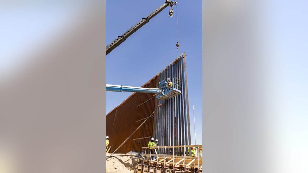 Workers install the first panels of the Calexico border wall project