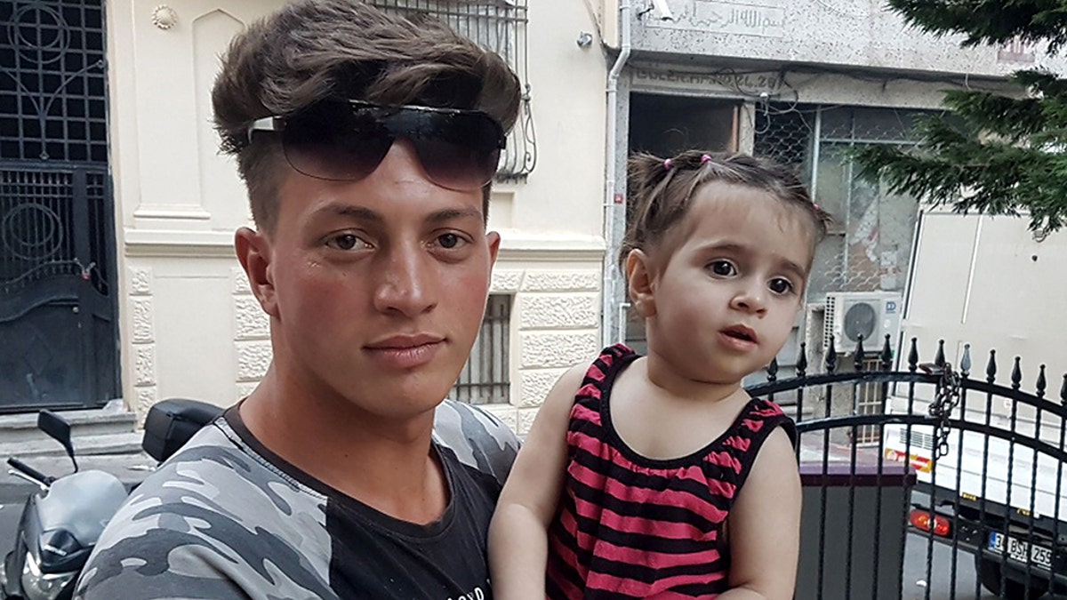 Algerian citizen Fawzi Zabaat (L), 17, poses with Syrian toddler Doha Muhammed he caught as she was falling from the second floor at Fatih district in Istanbul on June 27, 2019. (Photo by STR / DHA / AFP) / Turkey OUT (Photo credit should read STR/AFP/Getty Images)