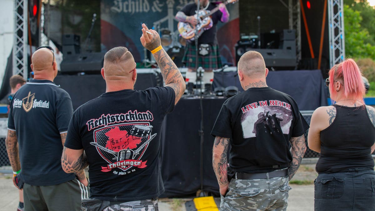 Three men and a woman watch a stage at the Shield and Sword Festival. (Photo by Daniel Schäfer/picture alliance via Getty Images)