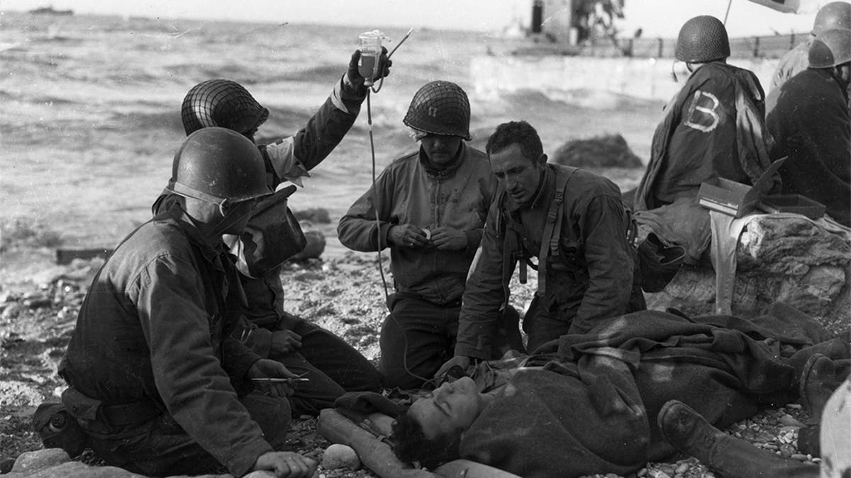 FILE -- June 12, 1944: American medics administer a plasma transfusion to a survivor of a landing craft sunk off the coast of northern France. (Photo by Weintraub/MPI/Getty Images)