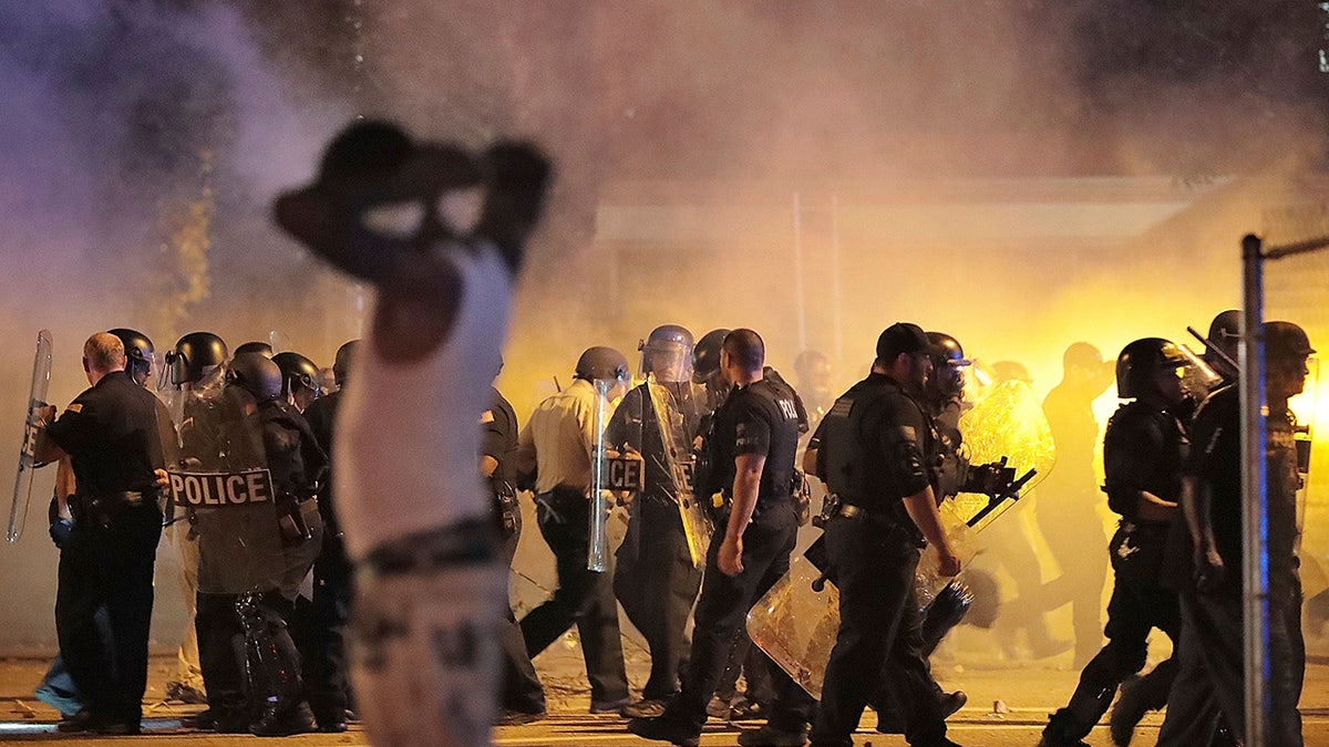 Police retreat under a cloud of tear gas as protesters disperse from the scene of a standoff after Frayser community residents took to the streets in anger against the shooting of a youth by U.S. Marshals earlier in the evening, Wednesday, June 12, 2019, in Memphis, Tenn. (Jim Weber/Daily Memphian via AP)