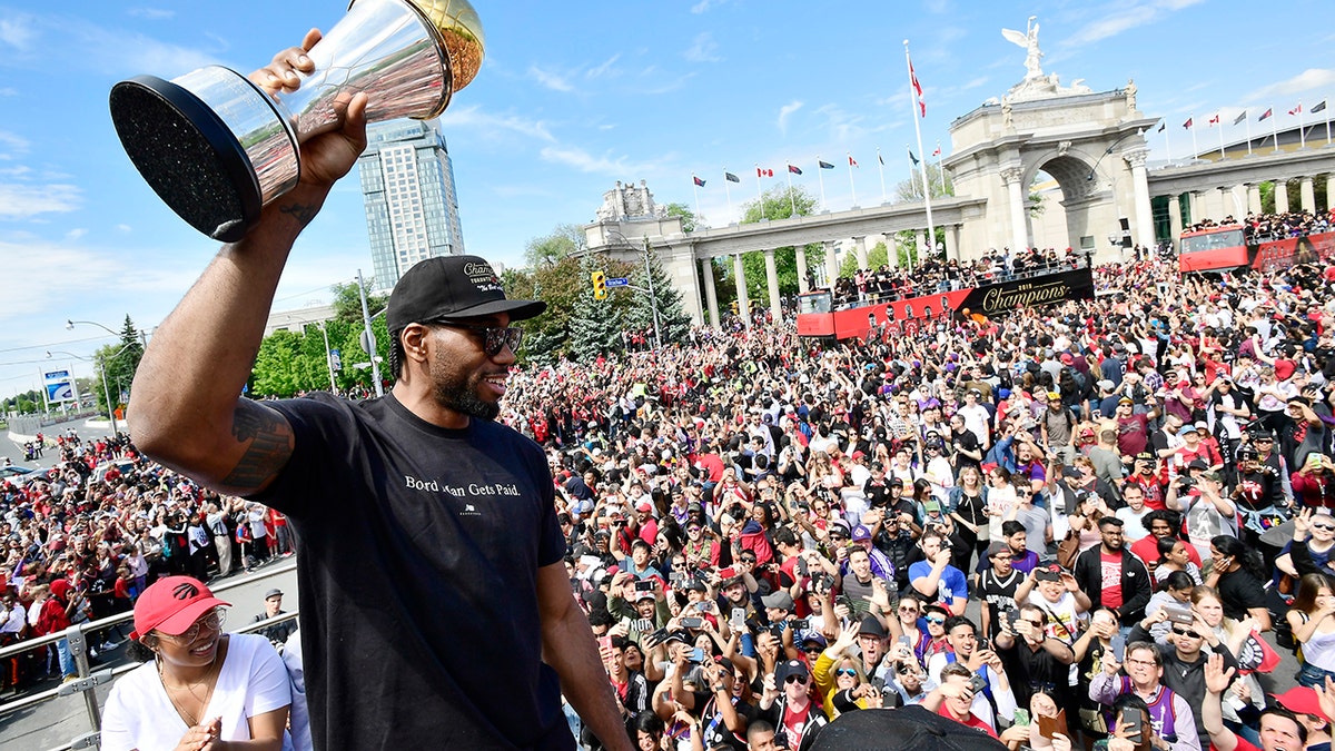 Toronto Raptors forward Kawhi Leonard holds his playoffs MVP trophy during the NBA basketball championship team's victory parade in Toronto, Monday, June 17, 2019. (Frank Gunn/The Canadian Press via AP)