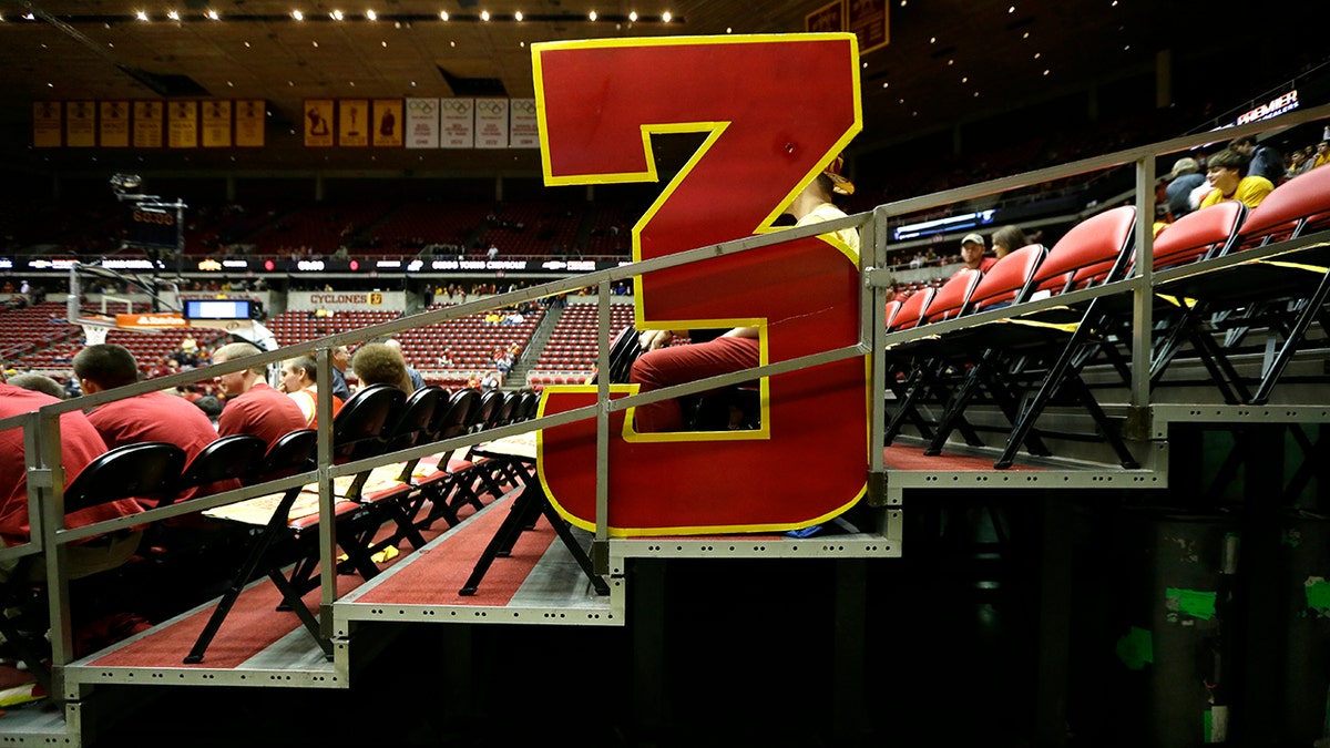 FILE - In this Jan. 17, 2015, file photo, a large 3-point sign sits in the stands before an NCAA college basketball game between Iowa State and Kansas, in Ames, Iowa. The NCAA Playing Rules Oversight Panel announced Wednesday that the arc will be moved to 22 feet, 1 3/4 inches for the 2019-20 season, matching the international distance. (AP Photo/Charlie Neibergall, File)