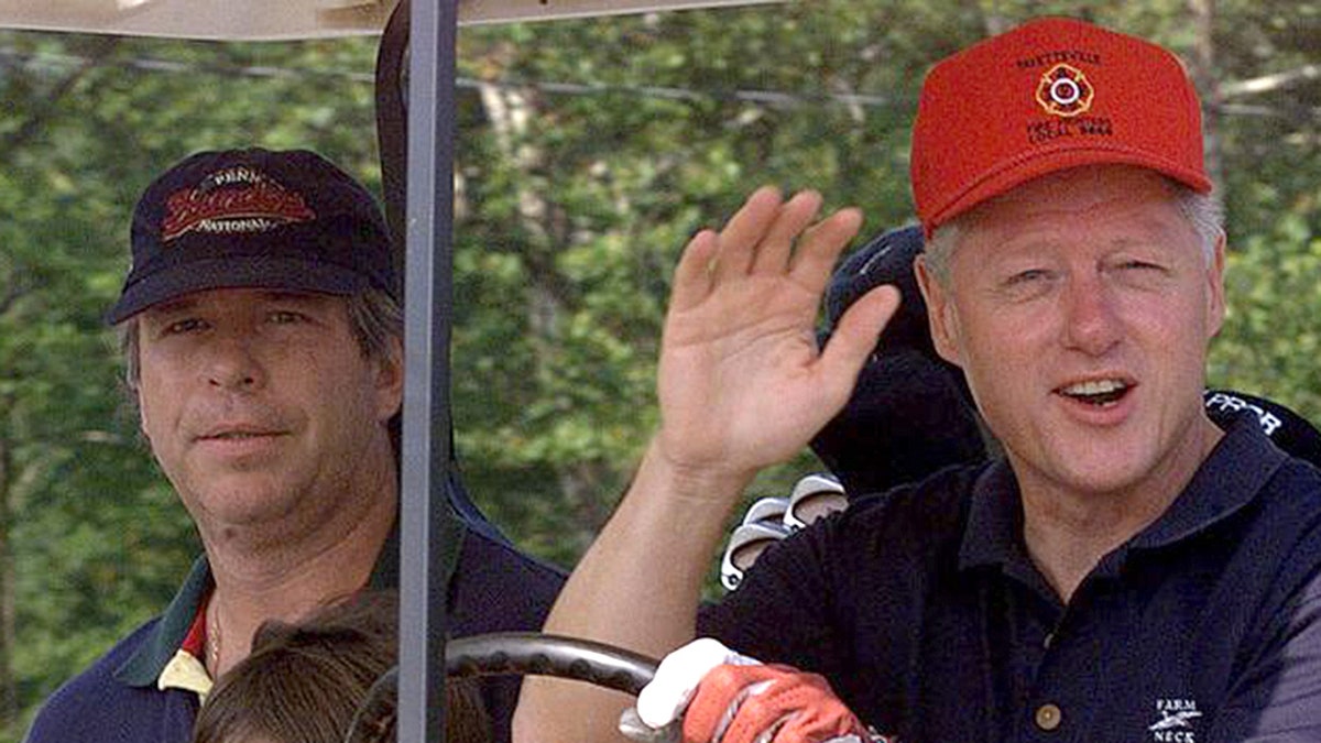 President Clinton waves to reporters as he and brother-in-law Tony Rodham, left, drive off for a round of golf at Maple Run Golf Course Saturday, Aug. 14, 1999, in Thurmont, Md. (AP Photo/Khue Bui)