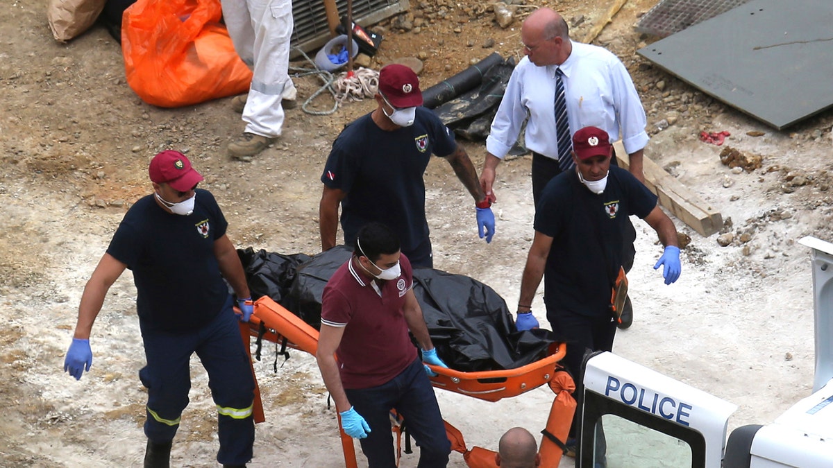 Cyprus Special Disaster Response Unit investigators carry a covered suitcase on a stretcher after it was retrieved from a man-made lake near the village of Mitsero, outside of the capital Nicosia, Cyprus, Tuesday, June 4, 2019. (AP Photo/Petros Karadjias)